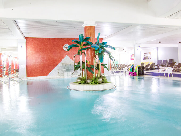 Ein Innenpool mit einer Palme im Zentrum bringt tropischen Flair.