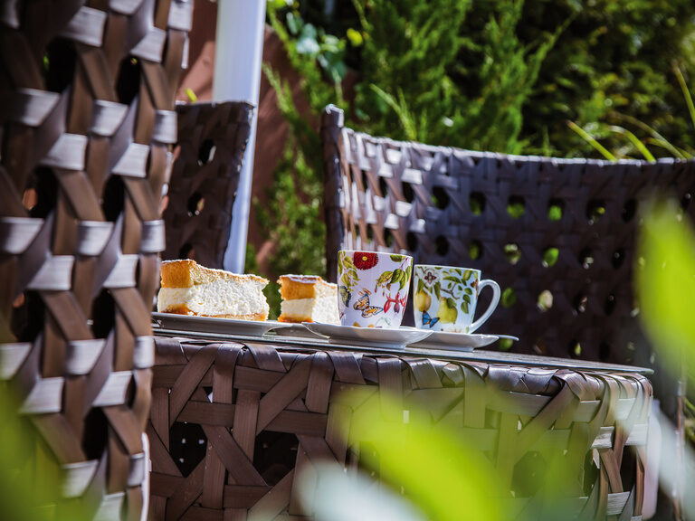 Auf einem Gartentisch ist für Kaffee und Kuchen gedeckt